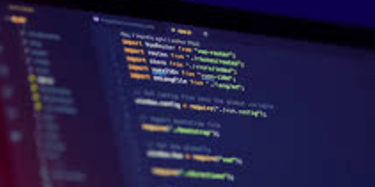 Programuotojas prie kompiuterio ekrano su programavimo kodu, simbolizuojantis etišką įsilaužimą